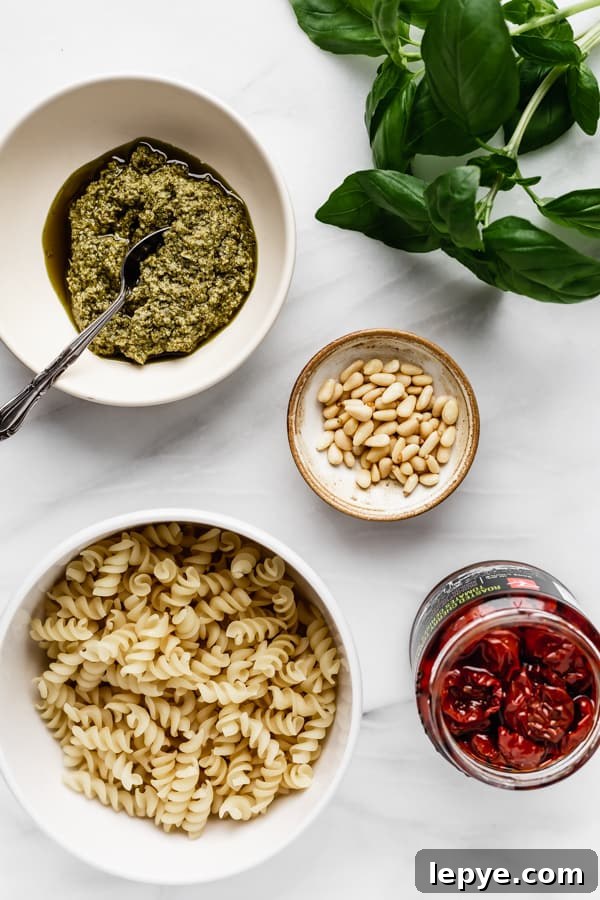 pesto, basil, pine nuts, sun-dried tomatoes and pasta on a marble board