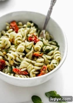 a close up image of a bowl of pesto pasta salad