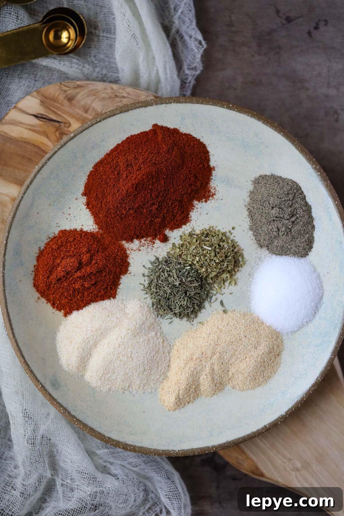 cajun seasoning ingredients on a gray plate on a wooden cutting board.