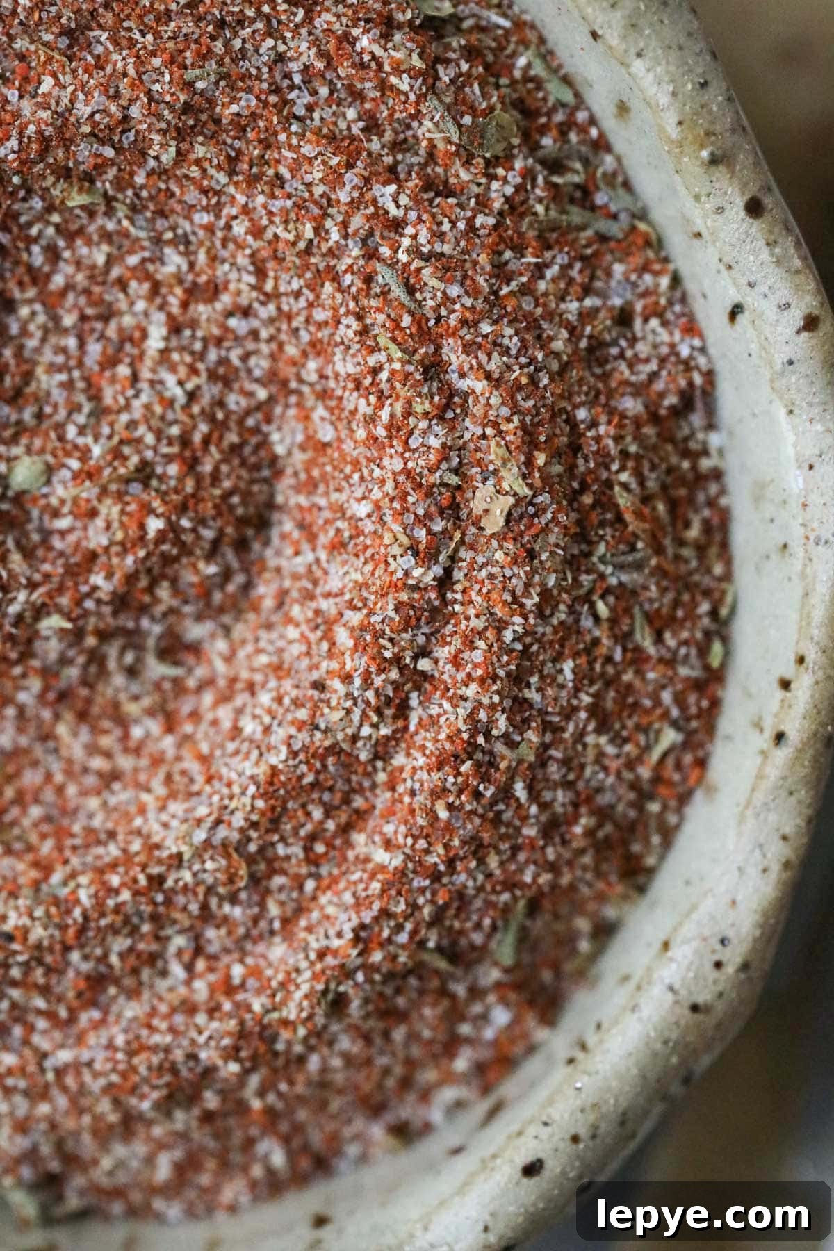cajun seasoning in a brown bowl on a wooden cutting board.