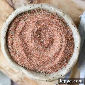 cajun seasoning in a brown bowl on a wooden cutting board.