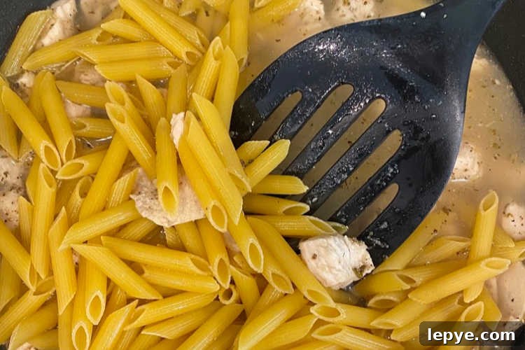 penne pasta, water and chicken in skillet