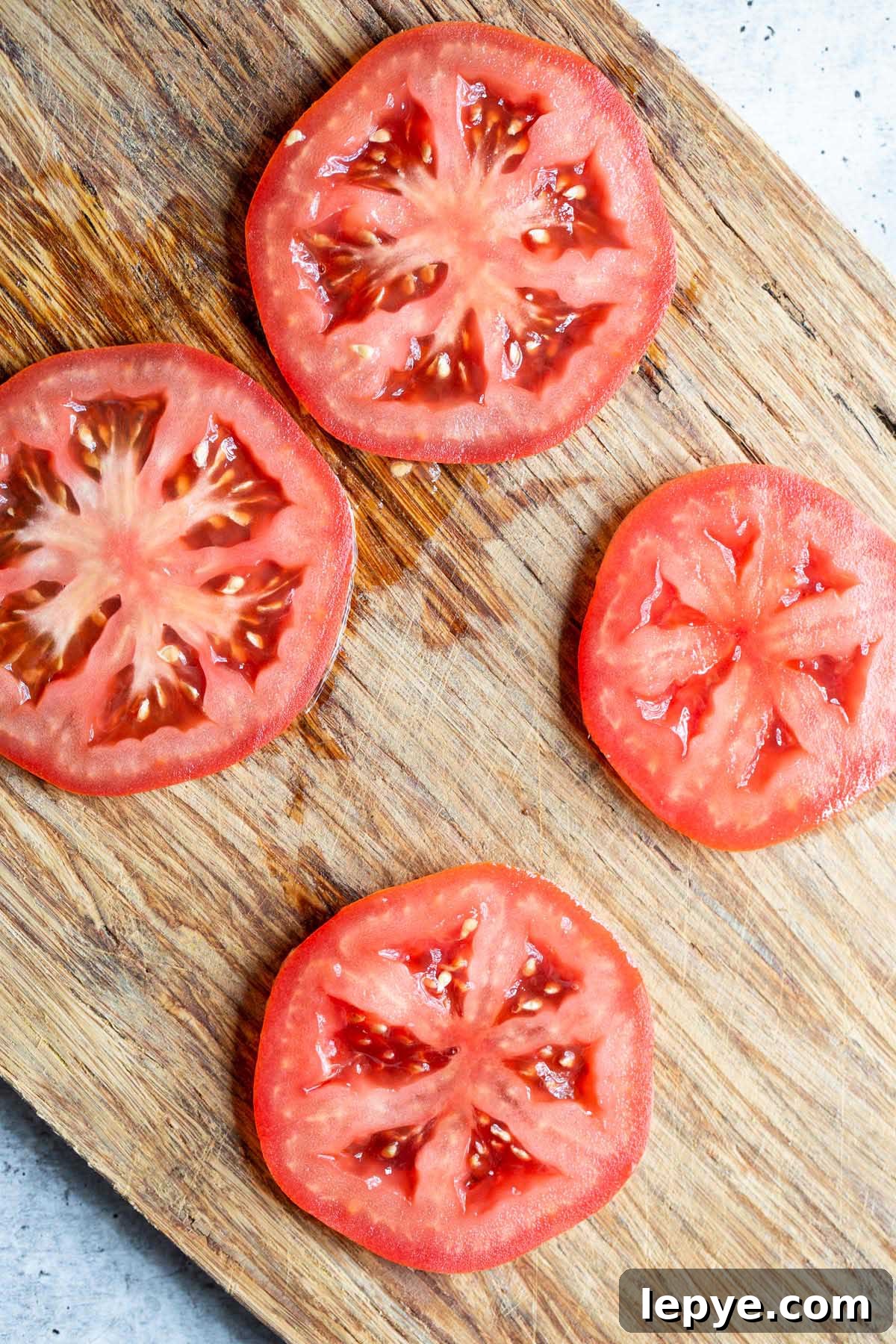 Crispy Parmesan Air Fryer Tomatoes Recipe 3 Tomato slices on a cutting board.