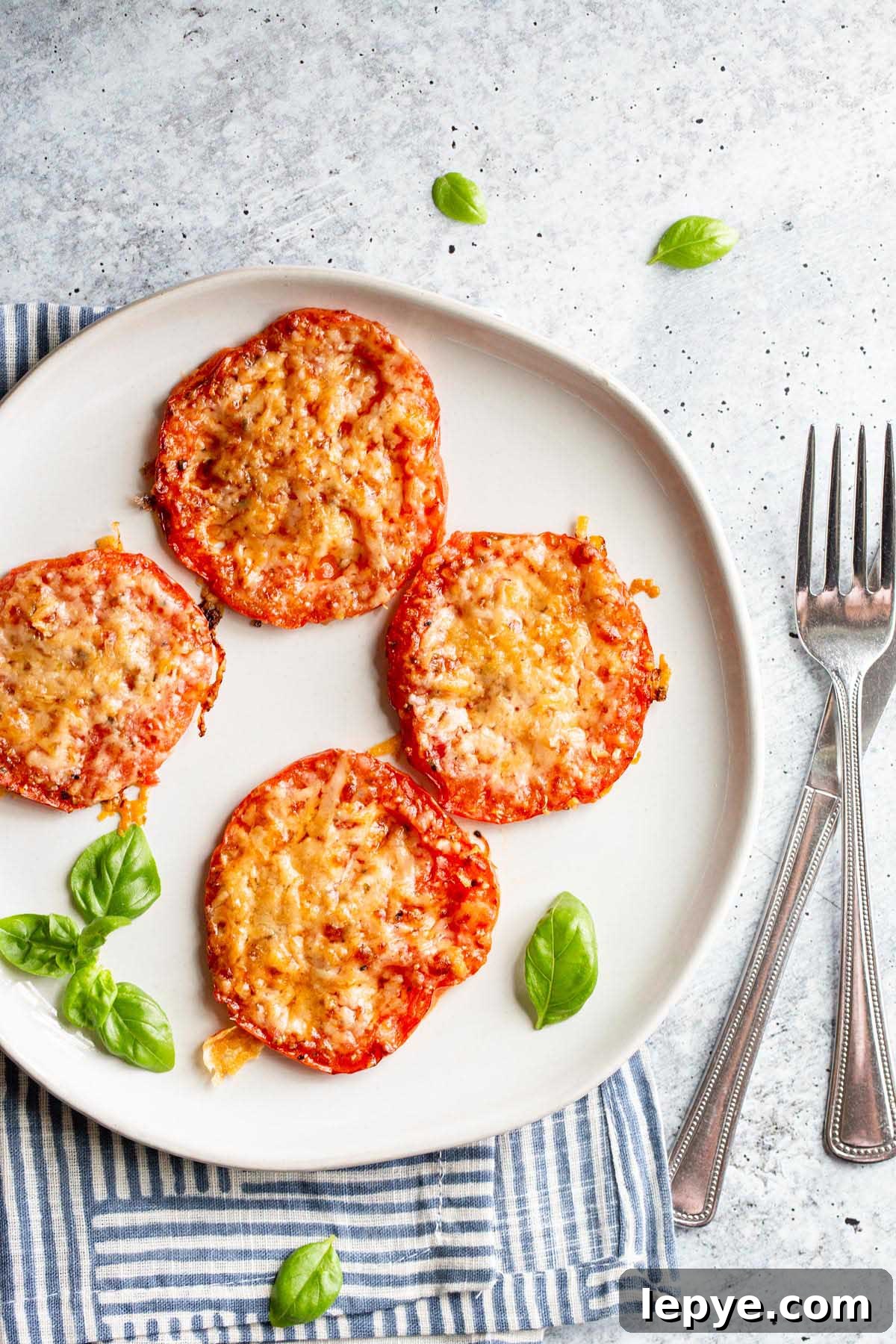 Crispy Parmesan Air Fryer Tomatoes Recipe 8 Roasted tomatoes with parmesan cheese on a white plate.