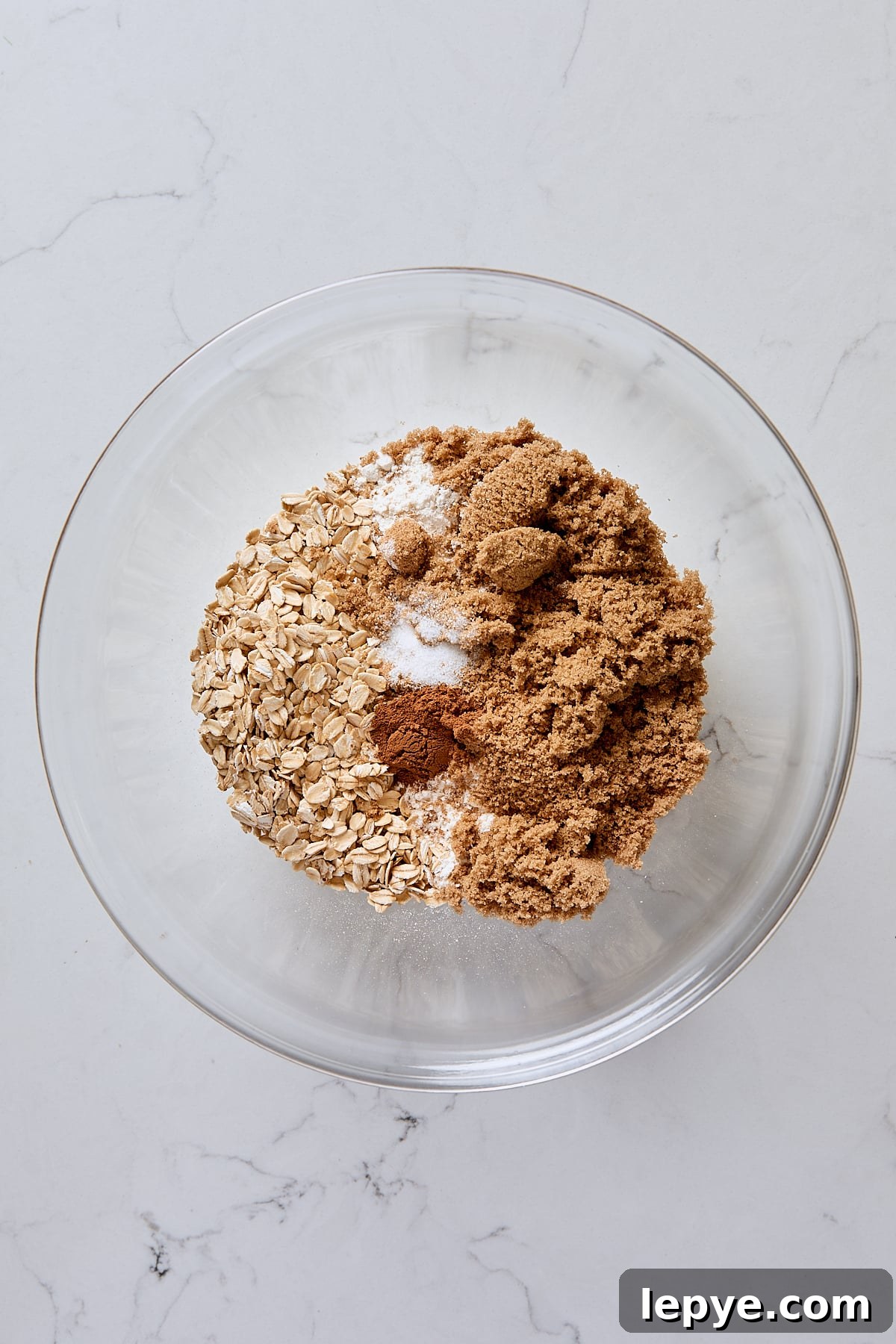 Rolled oats, flour, dark brown sugar, cinnamon, and salt in glass bowl