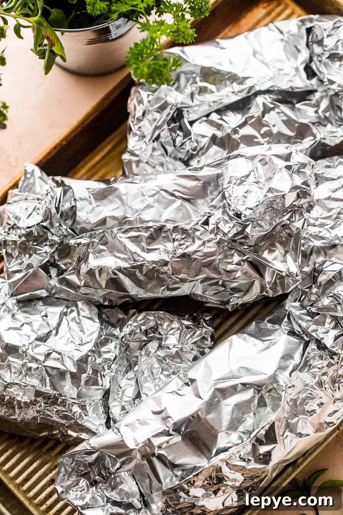 Chicken and Vegetables in Foil Packets combine juicy chicken and crisp veggies, all cooked together in foils for a convenient family meal. several foil packets arranged on a baking sheet.
