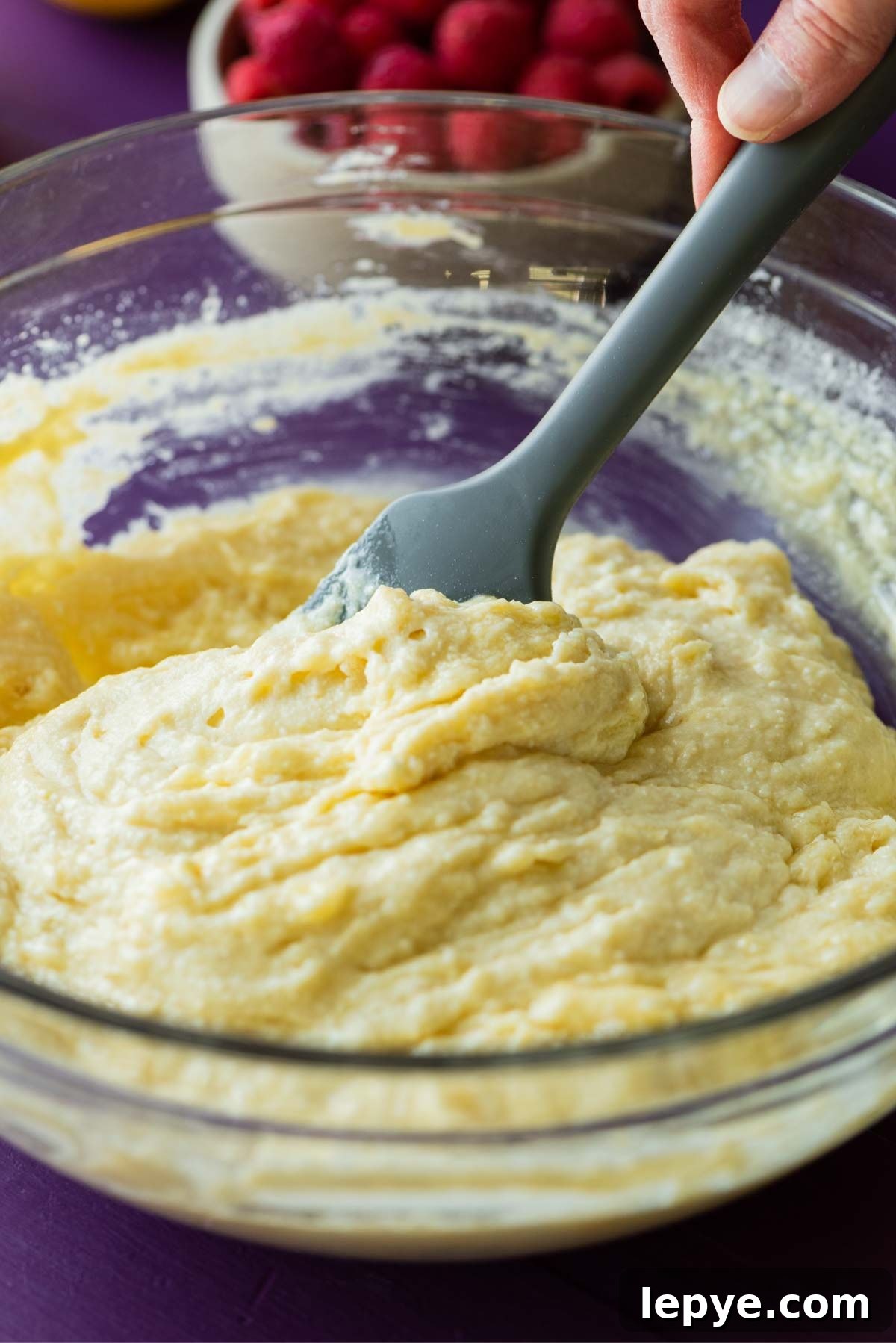Adding the dry ingredients to wet mixture to make lemon raspberry ricotta cake.