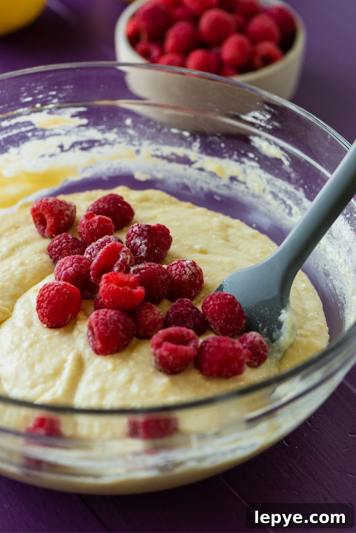 Folding in fresh raspberries to a lemon raspberry ricotta cake batter.