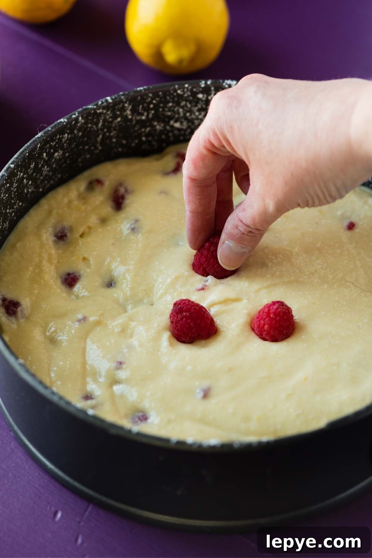 Topping the lemon raspberry ricotta cake with fresh raspberries before baking.