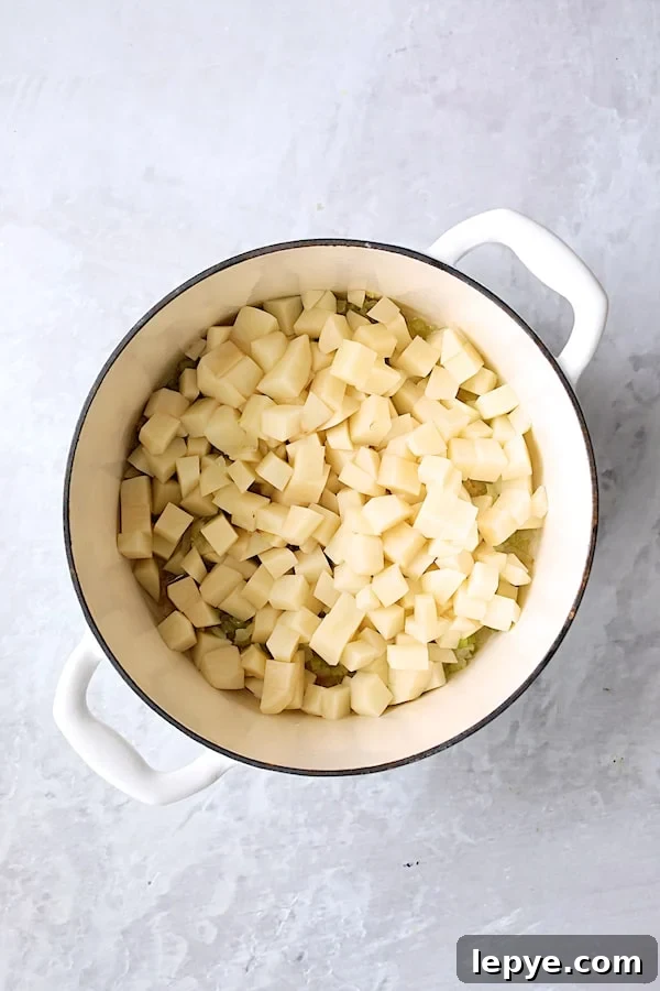 Creamy Kielbasa, Potato & Kale Soup Recipe 3 Photo of diced potatoes in white Dutch oven.