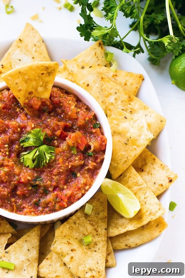 Top down shot of blender salsa in a white bowl with tortilla chips on the side.
