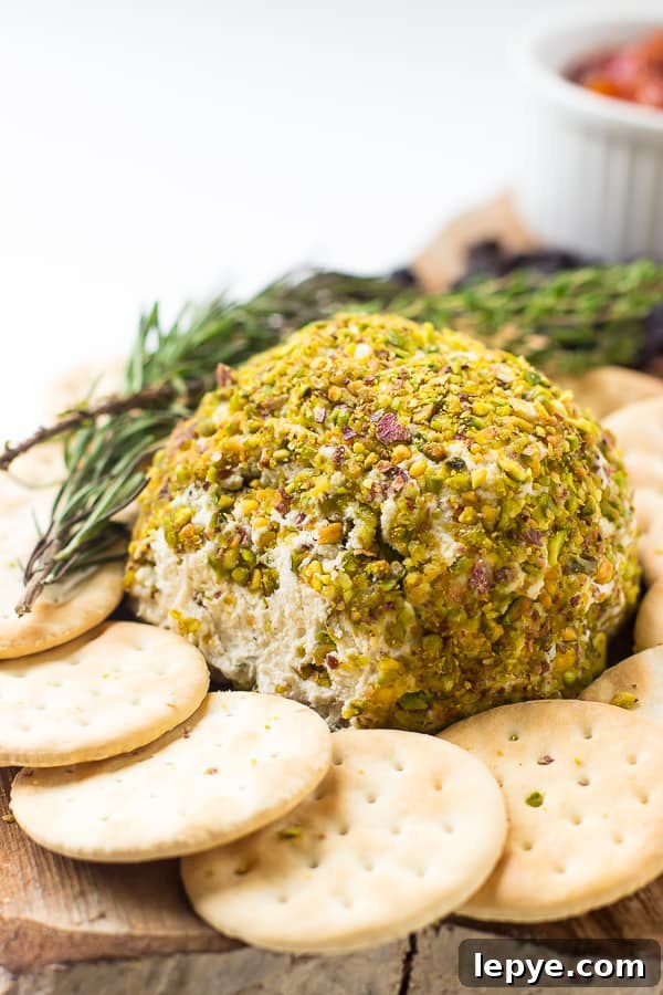 A vegan cheese ball on a wooden board surrounded by crackers.