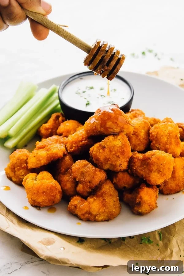 Honey being drizzled on cauliflower buffalo wings.