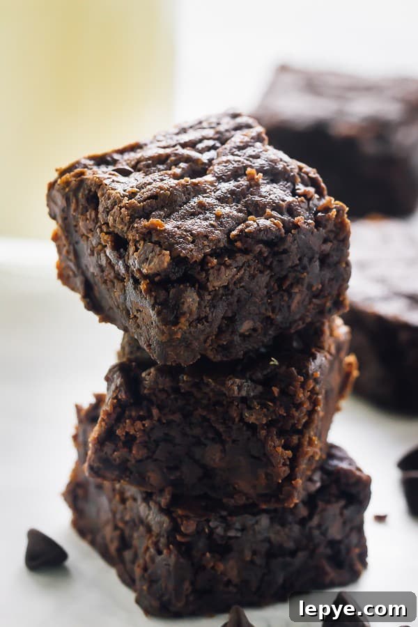 A stack of vegan brownies surrounded by chocolate chips.