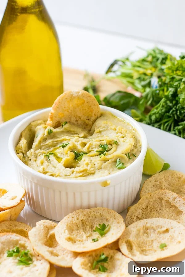 White bean dip in a white ramekin with chips on the side.