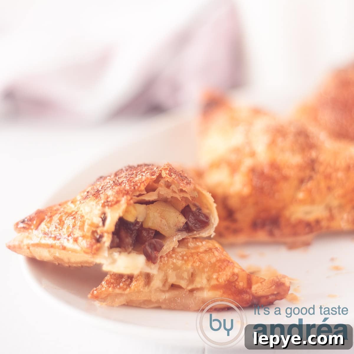 Dutch Appelflappen (Apple Turnovers) — Traditional Recipe & Tips 6 A square photo with an apple turnover cut open, showing the filling on a white background.