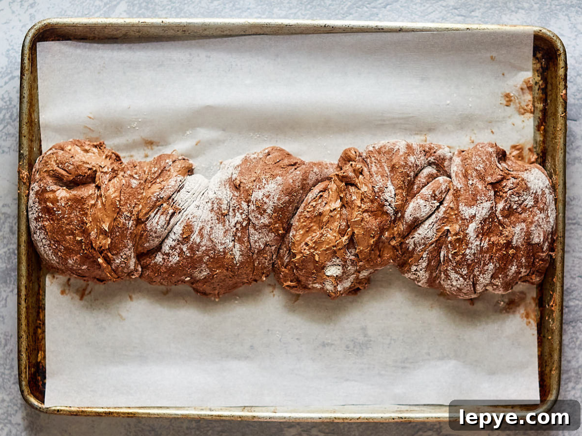 Classic Chocolate Babka Recipe: Swirled Yeast Bread Tutorial 9 Chocolate Babka Bread dough twisted and placed on a parchment paper-lined baking sheet - Hostess At Heart