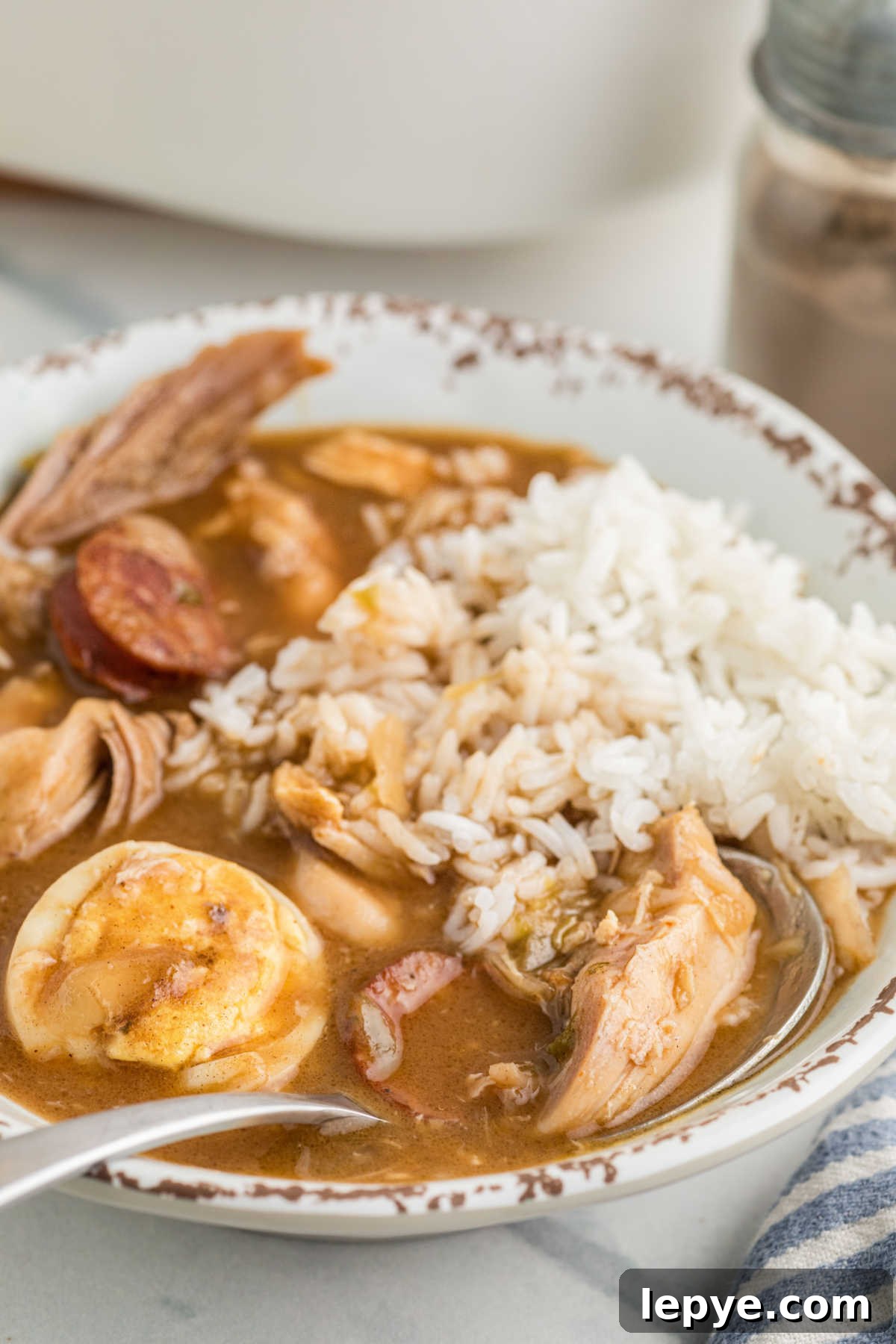 A bowl of turkey and andouille gumbo with a spoon resting.