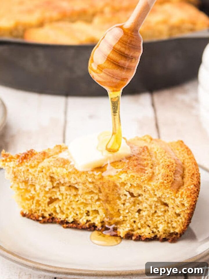 a piece of cornbread with a slice of butter on top and honey being poured over the top