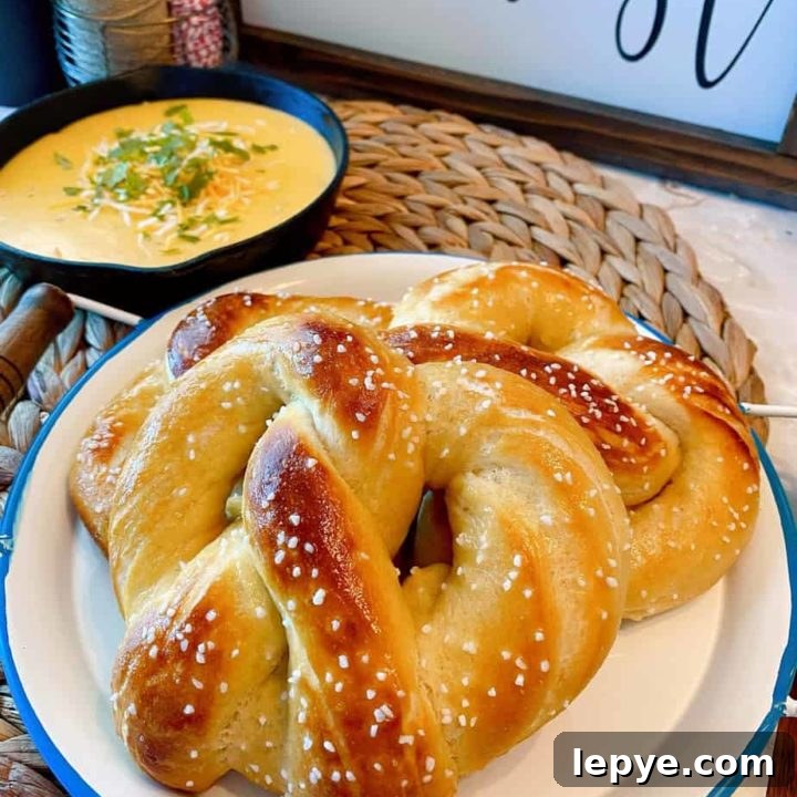 Easy Soft Homemade Pretzels on a plate with cheese dipping sauce in the background.