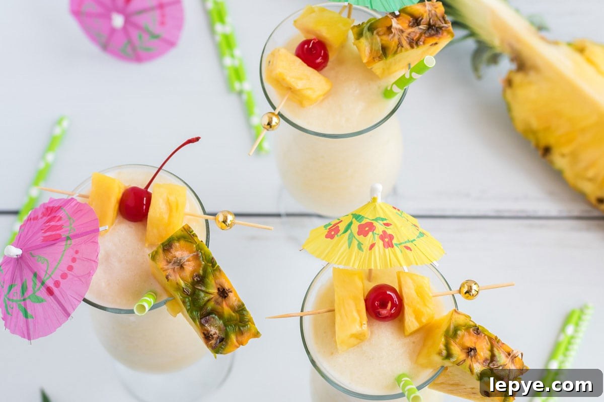 3 pina coladas with cherry and pineapple garnishes