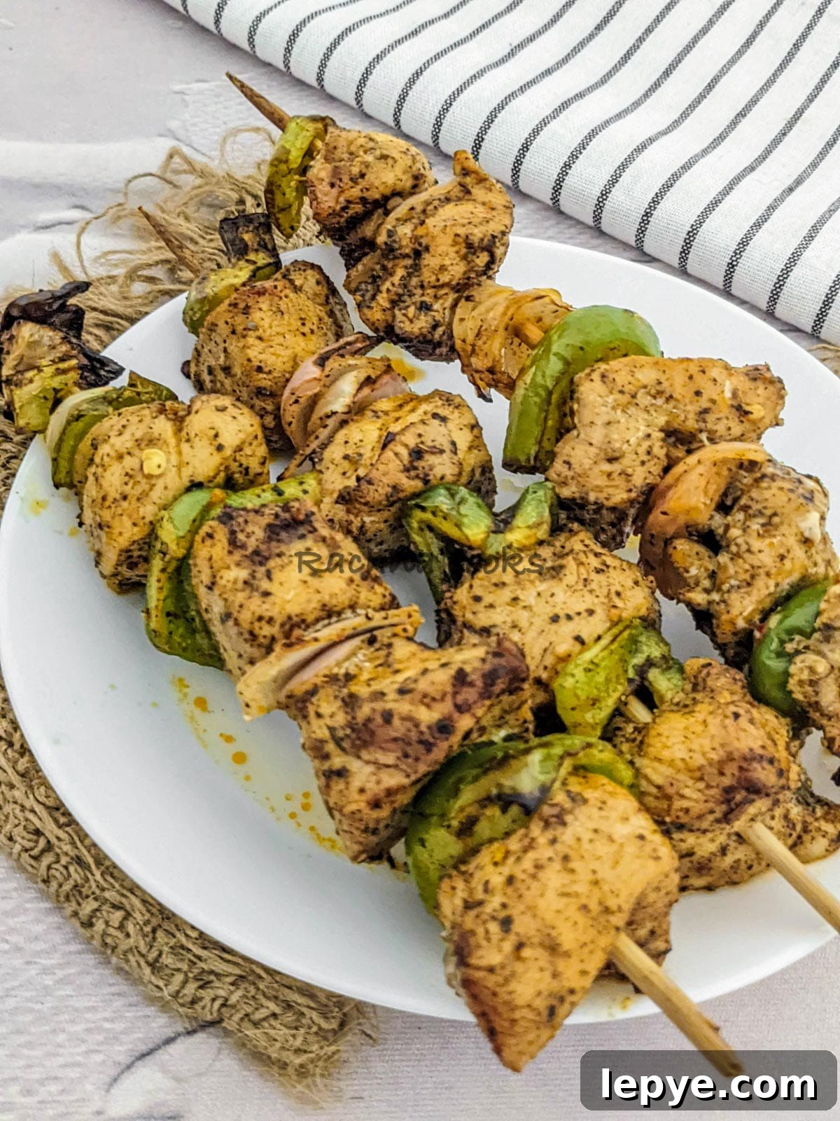 3 skewers of chicken kabob after air frying in a white plate.