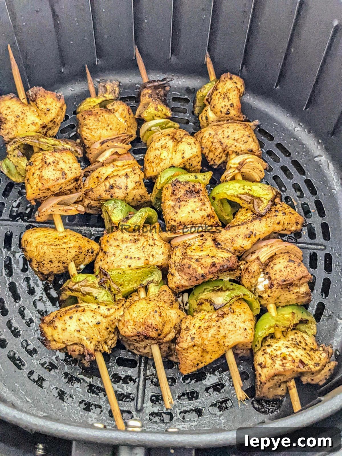 4 skewers of chicken kabob after air frying in air fryer basket.