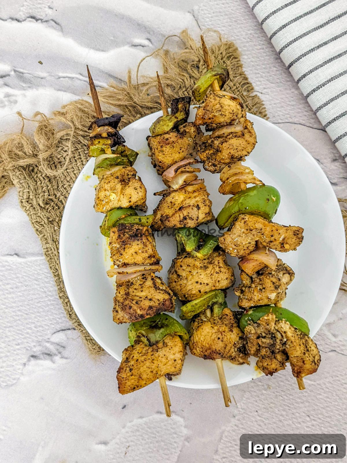 3 skewers of chicken kabob after air frying in a white plate.