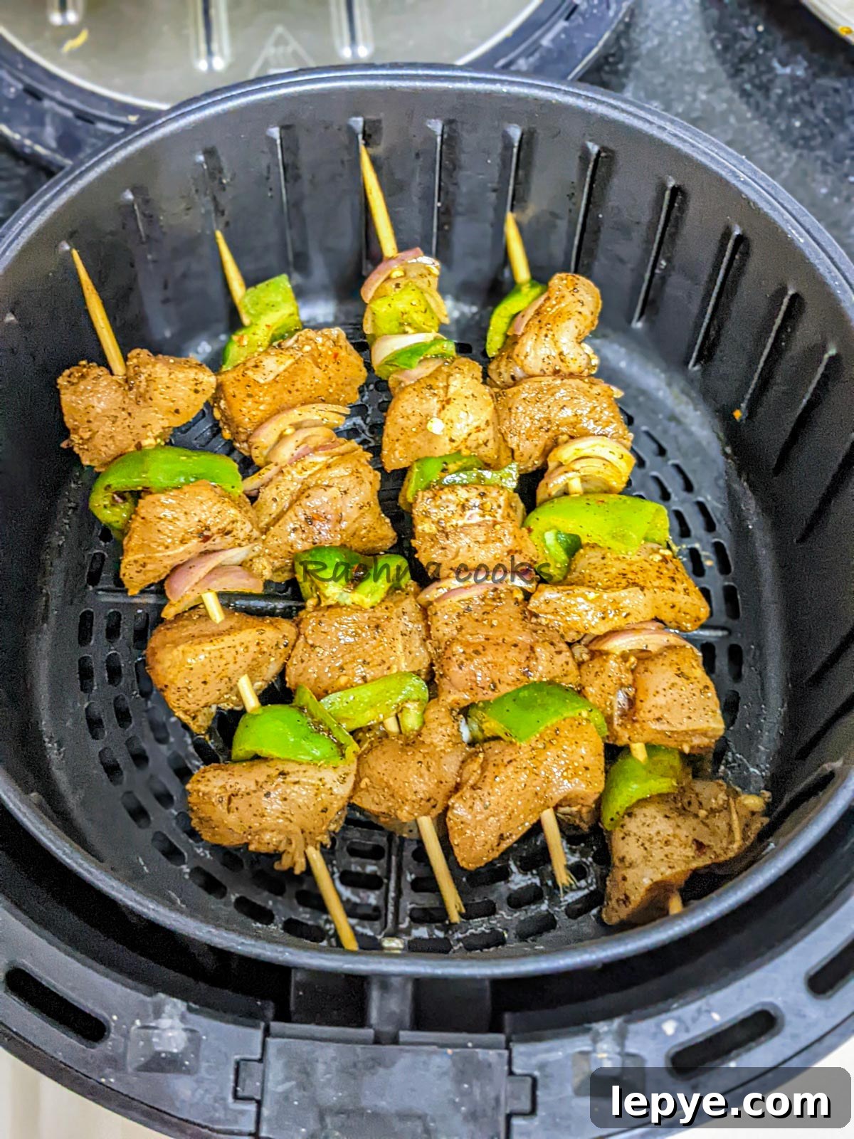 4 skewers of chicken kabob before air frying in air fryer basket.