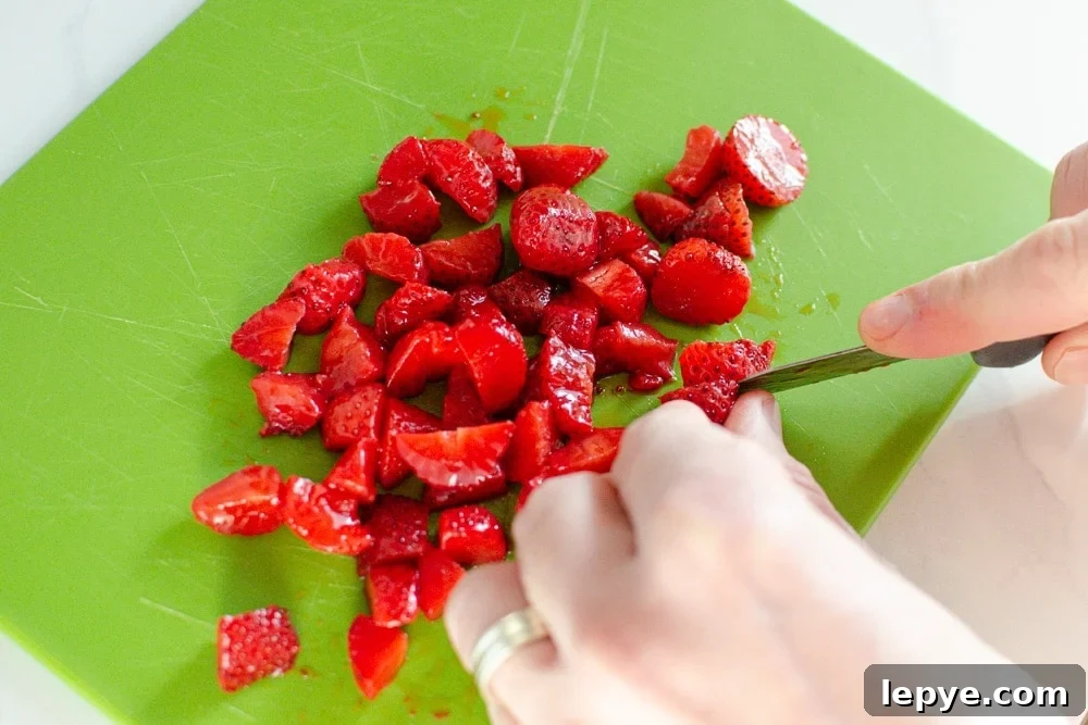 Strawberries chopped on green chopping board