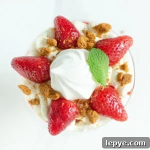 Crushed biscuit and mint leaf placed on top of the cream and strawberries in a glass to create our Eton mess dessert