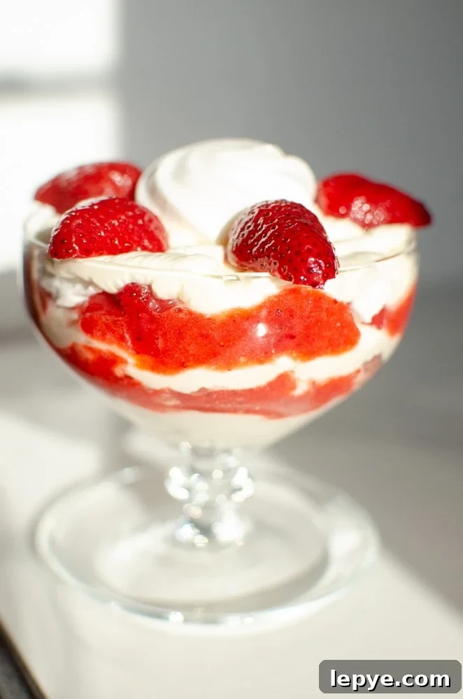 strawberries and a whole meringue has been placed on top of the cream