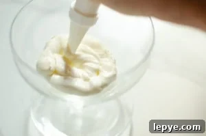 whipped cream being piped into a cold glass to make Eton mess dessert
