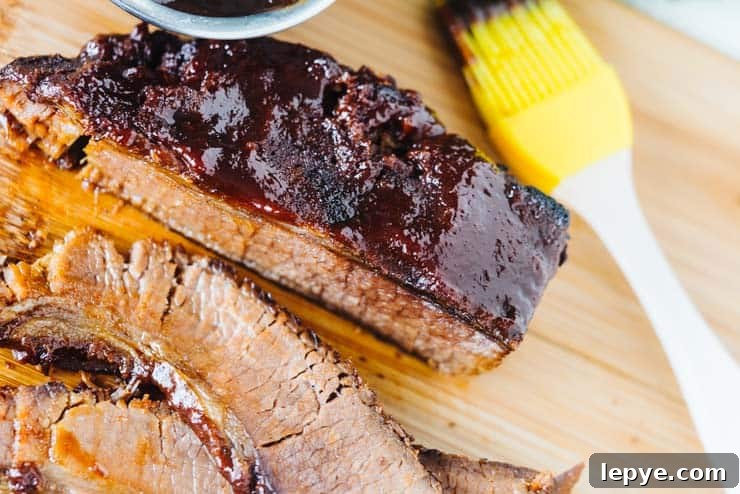 Sliced pressure cooker brisket on cutting board with yellow silicone basting brush