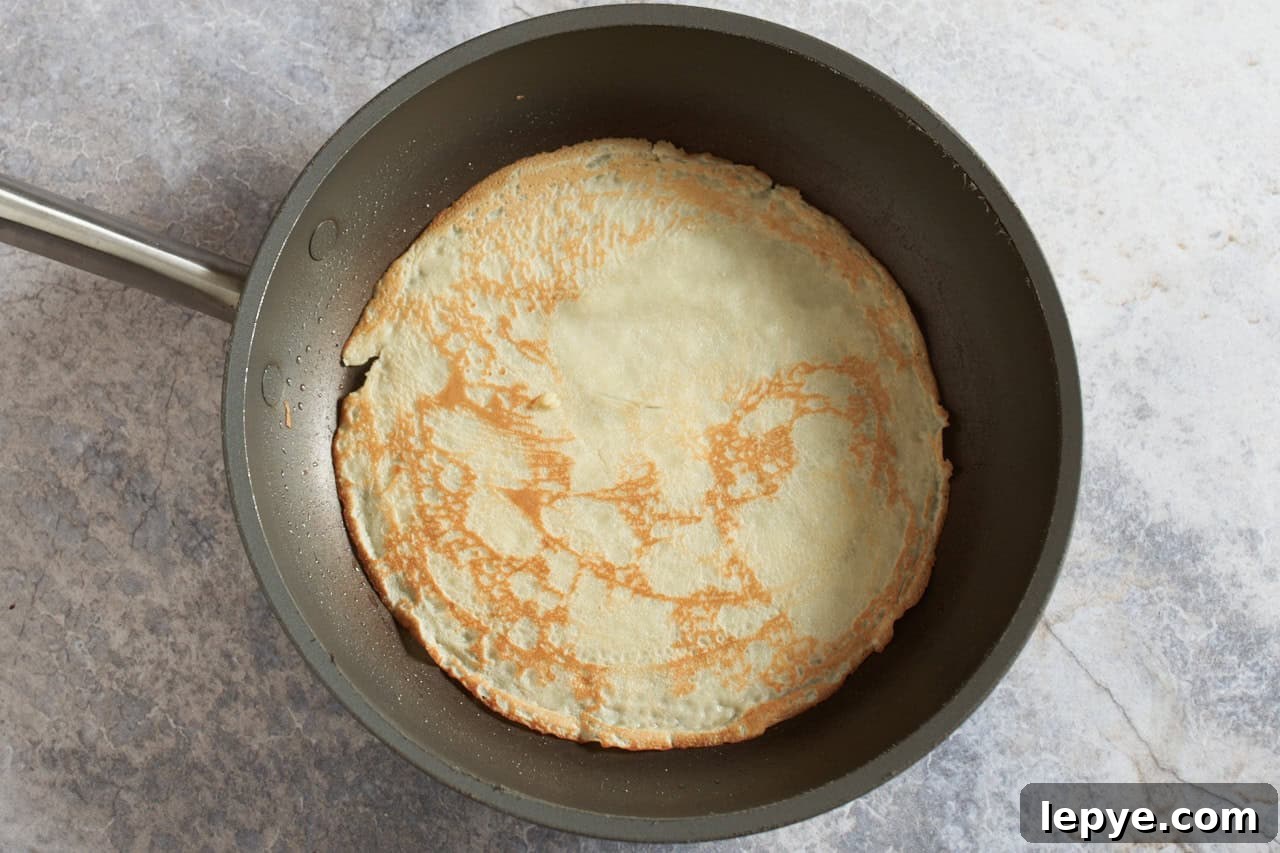 Sweet Nalysnyky: Classic Ukrainian Crepes with Cottage Cheese Filling 6 A crepe in a non-stick skillet.