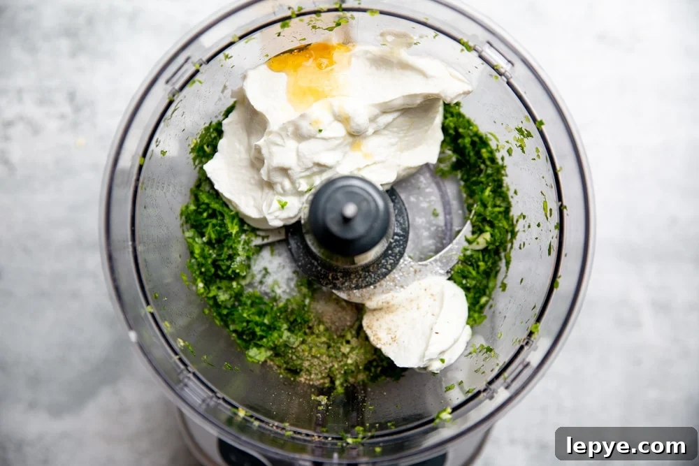 Process shot showing all of the ingredients for the yogurt sauce in a food processor. 