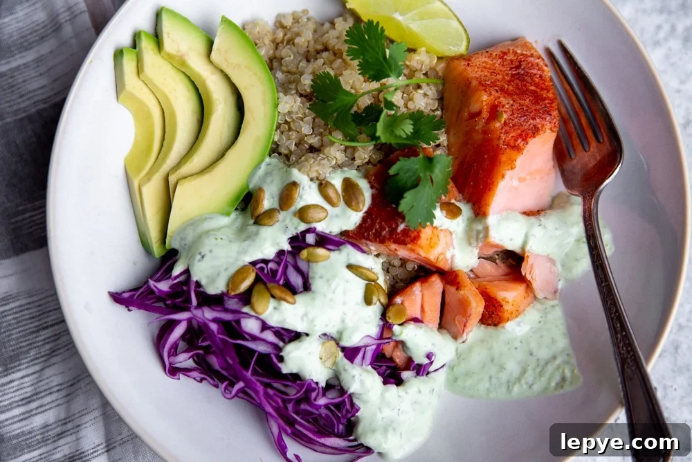 Close up of the cilantro yogurt sauce drizzled over a power bowl featuring salmon, avocado and shaved red cabbage. 