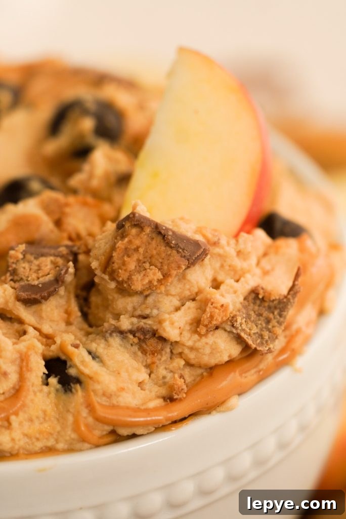 apple slice dipping into peanut butter cheesecake dip