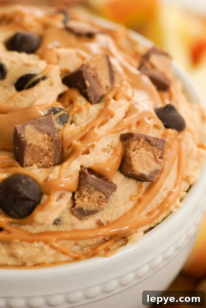 peanut butter cream cheese dip with Reese's cups, chocolate chips, and a peanut butter drizzle on top