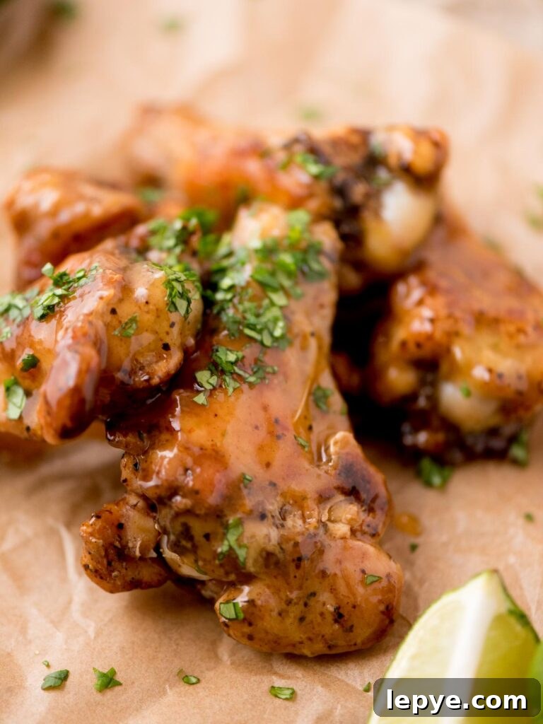 Citrus Tequila-Lime Chicken Wings Recipe for Game Day 10 Tequila lime glazed chicken wings with chopped cilantro served on parchment paper with a lime wedge.