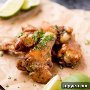 Citrus Tequila-Lime Chicken Wings Recipe for Game Day 12 Close up of tequila lime wings with chopped cilantro garnished on top laying on parchment paper.