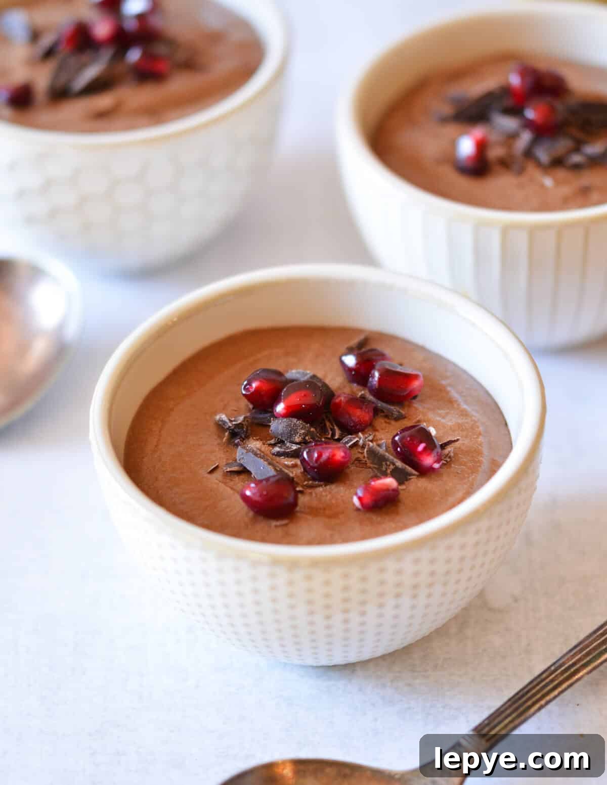Decadent Chocolate Mousse Recipe for Silky, No-Bake Perfection 2 chocolate mousse with chocolate shavings and pomegranate seeds on top.