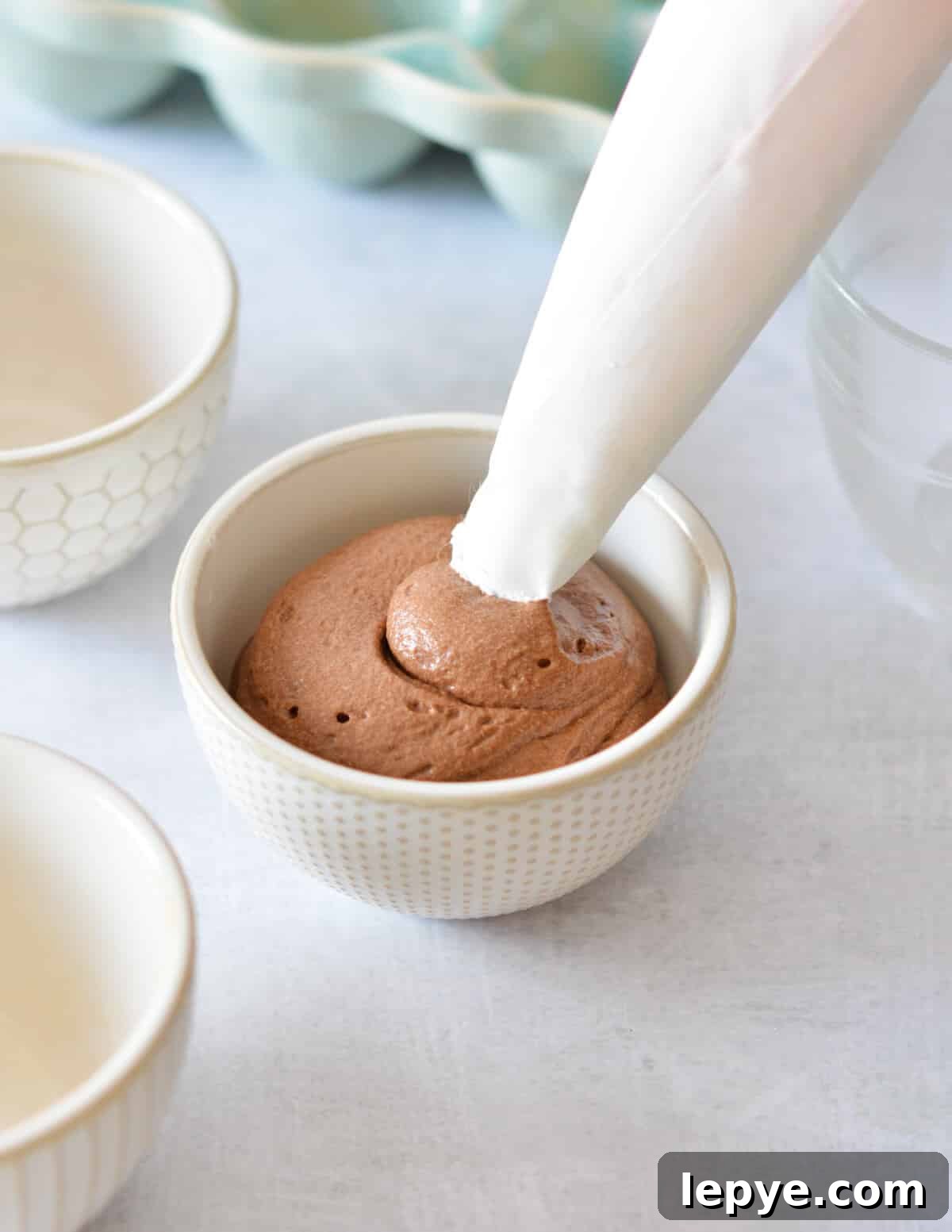 Decadent Chocolate Mousse Recipe for Silky, No-Bake Perfection 18 piping chocolate mousse into a small bowl.