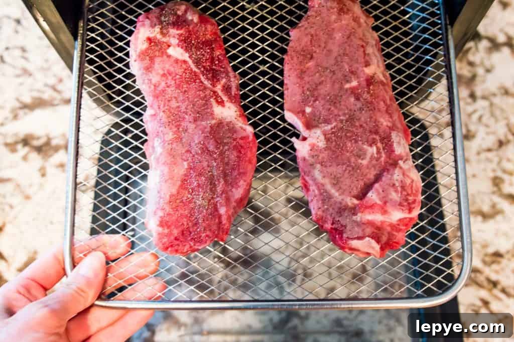 Frozen steaks on the rack of an air fryer.