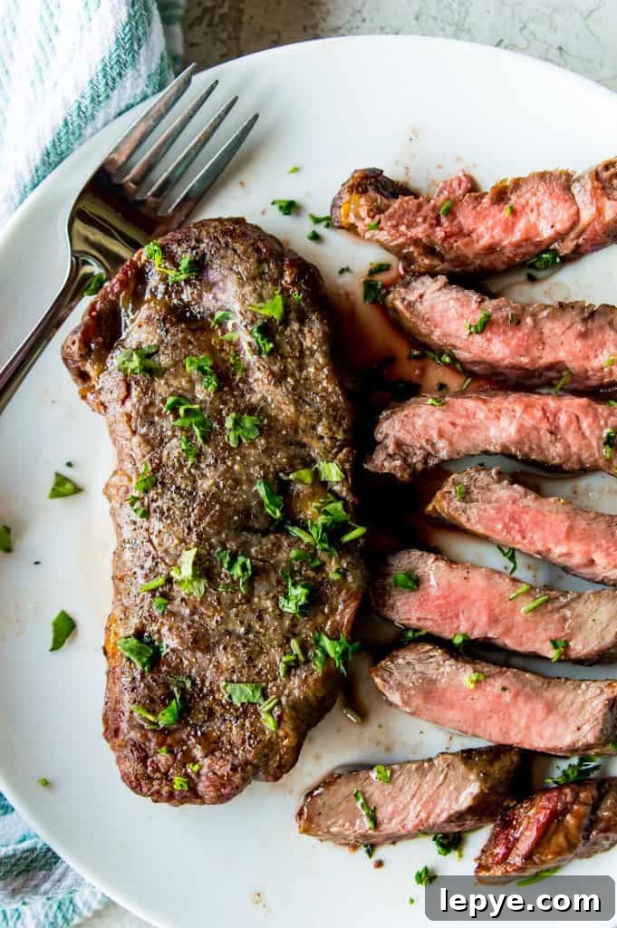 A cooked steak on a plate with pieces of cut up steak next to it.
