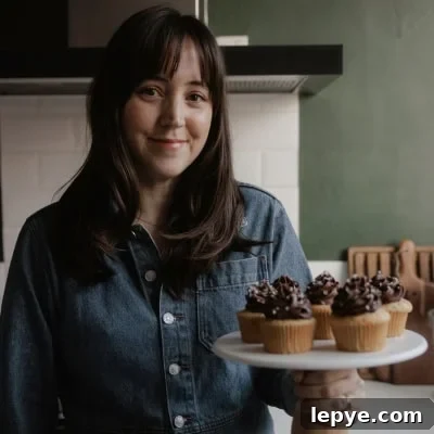 Danish Butter Cookies Dipped in Rich Chocolate 12 Ella from Alpine Ella is holding a cake stand with cupcakes on it.