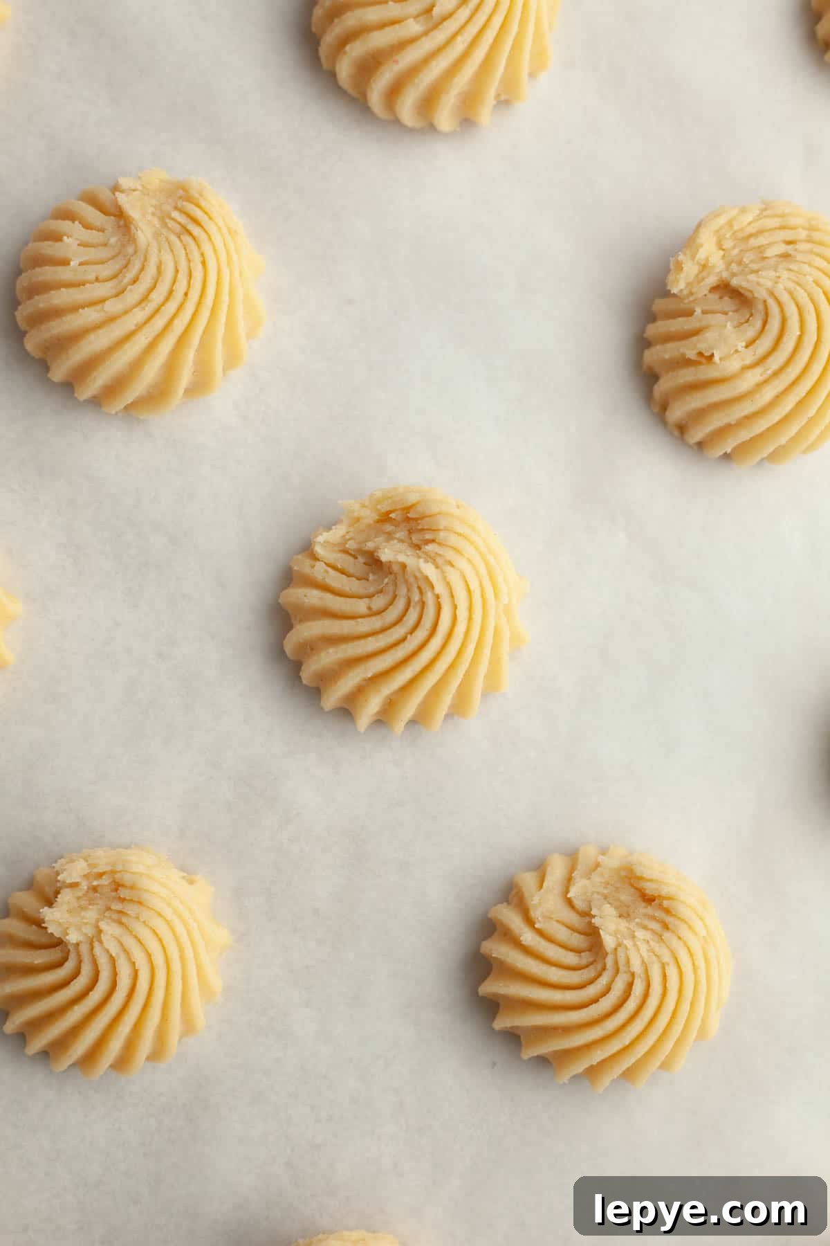 Danish Butter Cookies Dipped in Rich Chocolate 7 Piped Danish butter cookies on parchment paper.