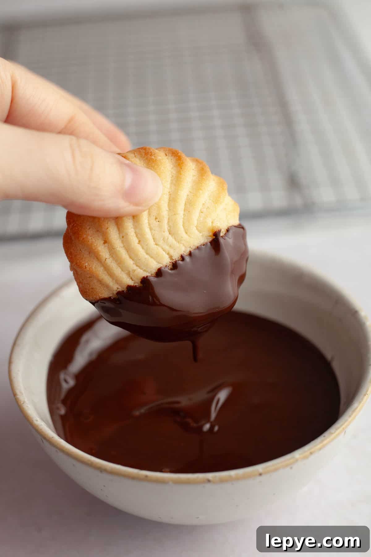 Danish Butter Cookies Dipped in Rich Chocolate 9 A hand dipping a piped butter cookie in melted chocolate.