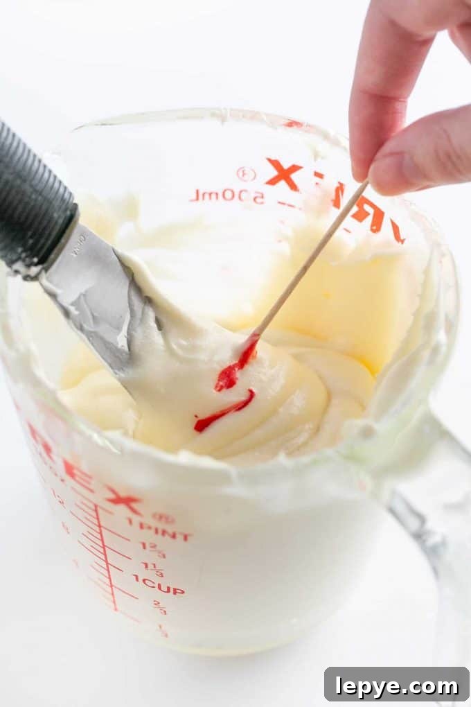 Cream Cheese Frosting Recipe for Cookies: Smooth & Spreadable 7 Adding red food coloring with toothpick to cream cheese frosting for cookies