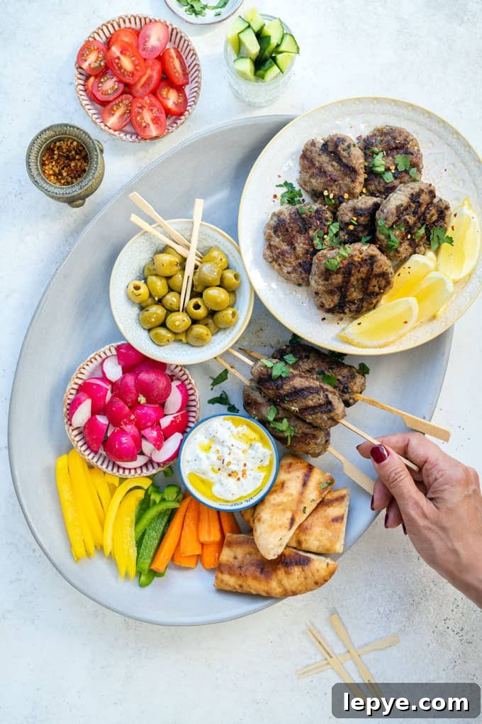 Authentic Lamb Kofta Recipe: Juicy Middle Eastern Meatballs 2 Platter with lamb kofta, tzatziki, olives, sliced vegetables and pita bread